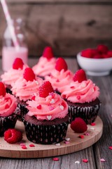 Chocolate cupcakes with pink cream, sugar hearts and fresh raspberries for  Valentine Day