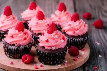 Chocolate cupcakes with pink cream, sugar hearts and fresh raspberries for  Valentine Day
