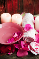Spa settings with roses. Fresh roses and rose petals in a bowl of water and various items used in spa treatments