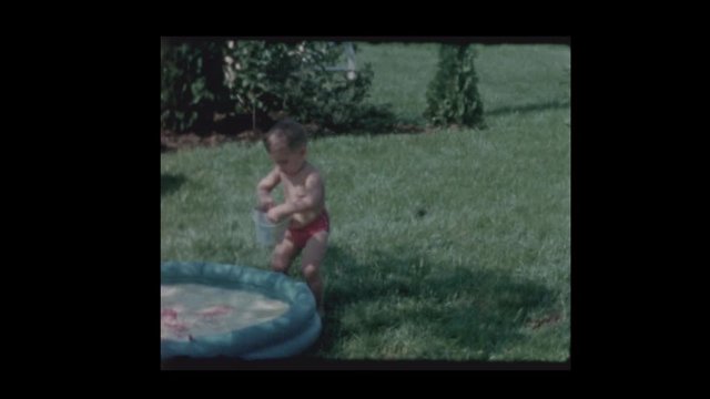 1961 Little boy plays with bucket in kiddie pool