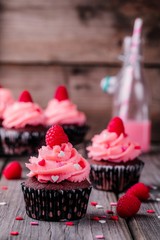 Chocolate cupcakes with pink cream, sugar hearts and fresh raspberries for  Valentine Day