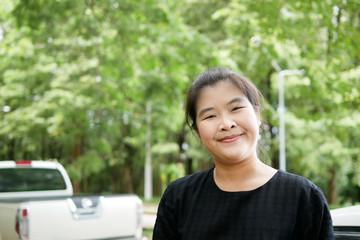 Young Asian Woman Smiling in a Car Parking Lot