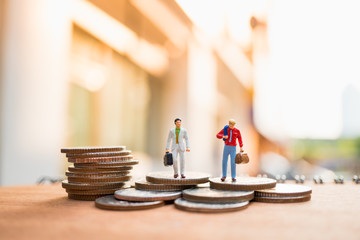 Miniature people, businessman standing on stack coins using as business concept