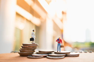 Miniature people, businessman standing on stack coins using as business concept