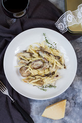 Garlic pasta with mushrooms. White plate, gray and wooden background.