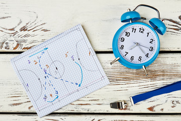 Development of game strategy. Notebook with drawn tactics, whistle and table clock. Work of football coach.