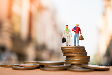 Miniature people, businessman standing on stack coins using as business concept