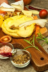 Small egg omelet on the kitchen board. Vegetables and spices.