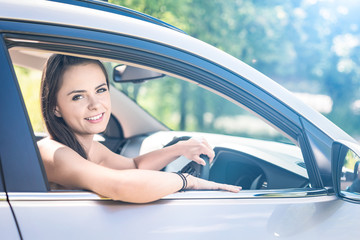 Beautiful young woman sitting in the interior of a new car with a smile.