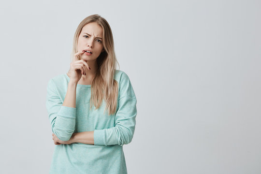 Indignant blonde female student being dissatisfied with results of exam or competition, can`t believe she made mistakes. Tired woman listens in displeasure lecture, keeps finger on opened mouth