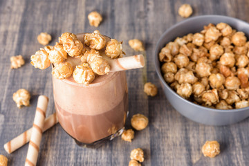 Glasses of chocolate milkshake with caramel popcorn. Iced cocoa drink and waffle on wooden background