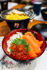 Salmon rice bowl served with ikura (salmon roe), crab, seaweed and wasabi with grilled corn and sliced potato at the restaurant in Sapporo in Hokkaido, Japan.
