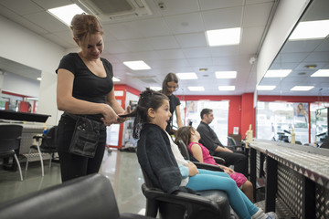 Hairdressers with little girls in beauty center saloon