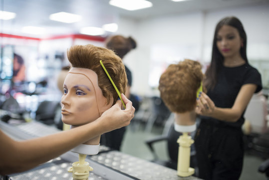 Hairdressers training with maniqui heads in barber shop school