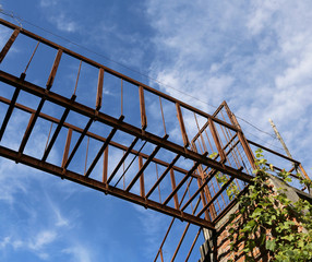 old suspended bridge of rusted iron outdoors and blue sky