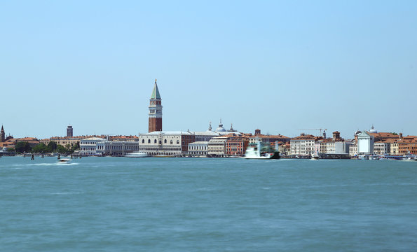 View of the island of venice with ancient palaces and bell towers with long exposure time and the wake of the movement of ships on the Venetian lagoon