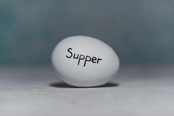An inscription on a chicken egg for a reminder of supper.