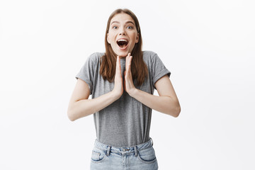Young cheerful attractive caucasian brunette girl with brown eyes in casual grey clothes clapping hand in excitement being chosen for the main role in university play.