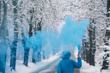 Person with blue bengal on the winter snowy road