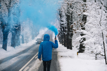 Person with blue bengal on the winter snowy road