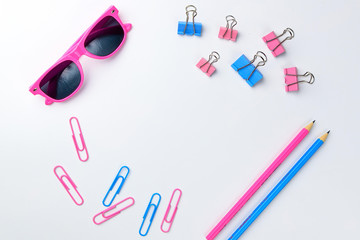 Stationary concept, Flat Lay top view Photo of Scissors, pencils, paper clips, sunglasses,sticky note,stapler and notepad in pink and blue tone on white background with copy space