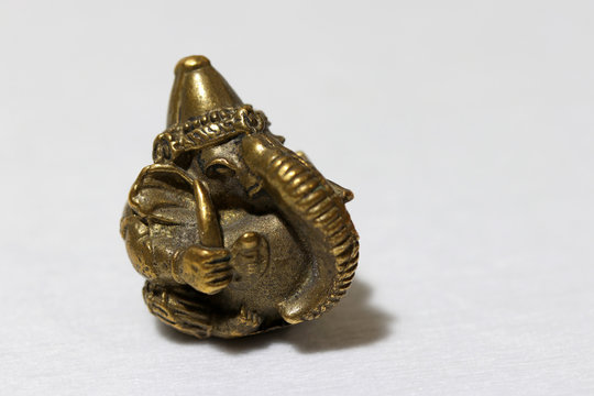 Mini Ganesha made from brass on white background, the son of Uma Devi god in Hinduism and Brahmanism. God of knowledge and arts.