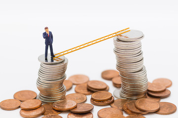Miniature people: Businessman thinking and standing on stack of coins with stair using as background money growth up, using as business concept.