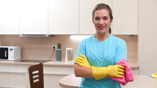 Cleaning company concept. Panoramic image of beautiful positive young woman - employee of cleaning company in rubber gloves with rag during cleaning