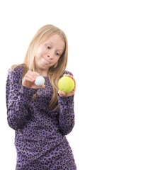 ein junges, blondes Mädchen vergleicht einen kleinen weißen Golfball mit einem großen, gelben Tennisball und wägt ab