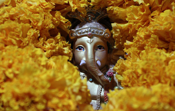 Ganesha made from brass among of yellow marigold flower, the son of Uma Devi god in Hinduism and Brahmanism. God of knowledge and arts.