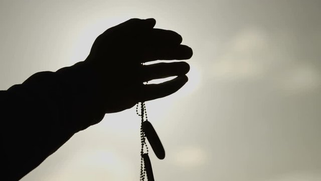 Hand in the sunlight release some dog tags, concept of those lost in war