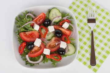 Traditional greek sallad with black olive on white plate on white background.
