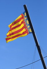 Flagge der Region Valencia im Wind wehend vor strahlend blauem Himmel