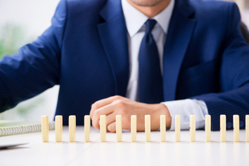 Young businessman playing with domino in office