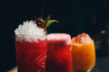 Glasses of cocktails on bar background