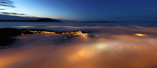 Fototapeta na wymiar Brasov City lights under the fog at dusk