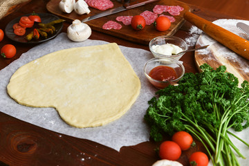 the chef makes a pizza heart for the Valentine's Day holiday. classic Italian pizza with salami and mozzarella