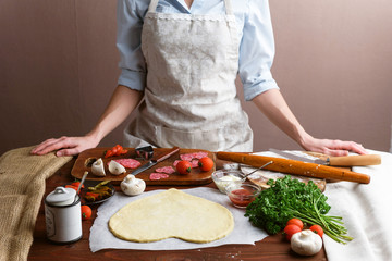 the chef makes a pizza heart for the Valentine's Day holiday. classic Italian pizza with salami and mozzarella