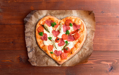 the chef makes a pizza heart for the Valentine's Day holiday. classic Italian pizza with salami and...