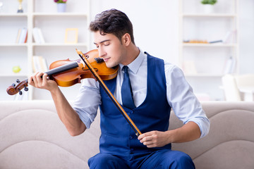 Young musician man practicing playing violin at home