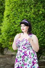 Fototapeta premium Young beautiful plus size Girl among the Evergreen plants in garden.