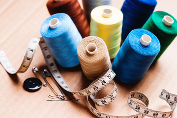 Pile of colorful spools of thread, buttons and measuring meter 