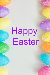 Pile of colorful eggs, candy and toys with Happy Easter card over white