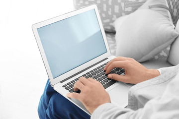 Young man using his laptop while sitting on sofa at home