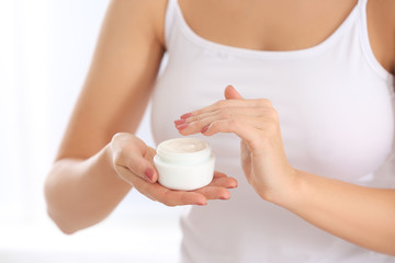 Young woman with jar of body cream, closeup