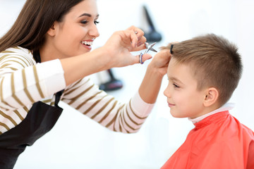 Female hairdresser working with little boy in salon, closeup