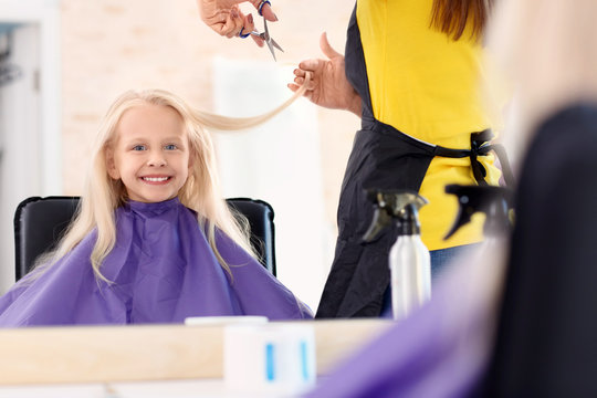 Female hairdresser working with little girl in salon