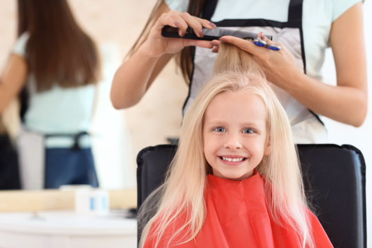Female hairdresser working with little girl in salon, closeup