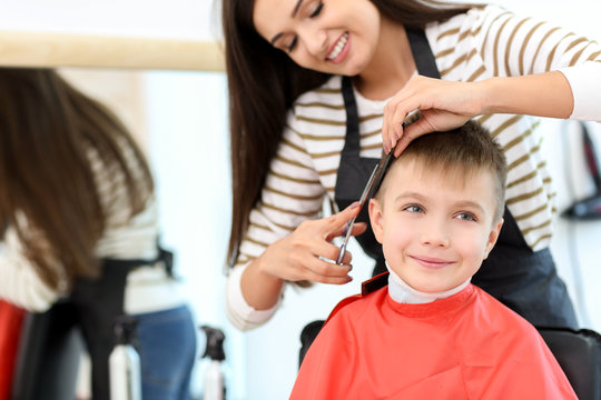 Female hairdresser working with little boy in salon, closeup
