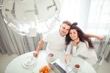 A modern young family using a laptop while having breakfast in the kitchen or dining room